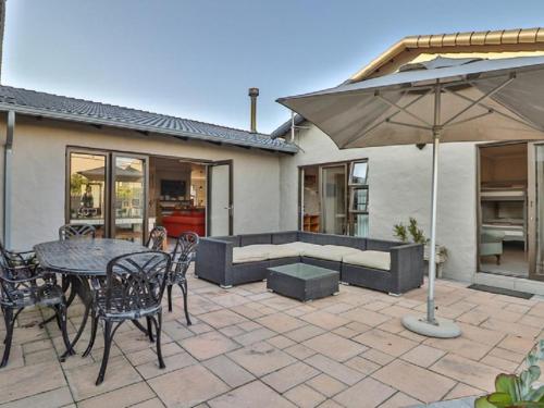 a patio with a table and chairs and an umbrella at Kamma Kai Beach Villa in Sedgefield