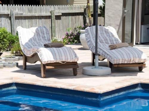 two chairs and an umbrella next to a swimming pool at Kamma Kai Beach Villa in Sedgefield