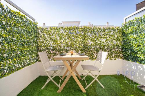une table et deux chaises devant une haie verte dans l'établissement Sunny Flat in Juan les pins, à Juan-les-Pins