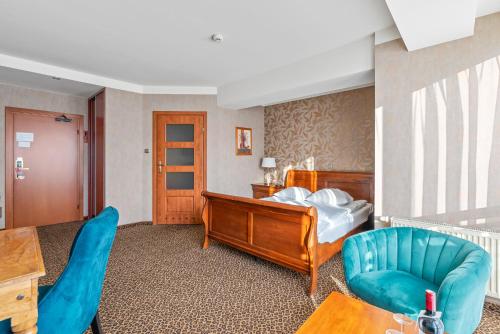a bedroom with a bed and a blue chair at Hotel Diament Vacanza Katowice - Siemianowice in Siemianowice Śląskie