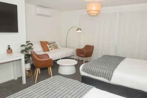 a hotel room with two beds and a desk and chairs at Murwillumbah Motor Inn in Murwillumbah