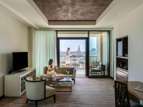 a woman sitting on a couch in a living room at Alwadi Hotel Doha - MGallery Collection in Doha