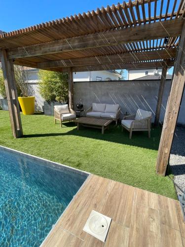 a backyard with a swimming pool and a wooden pergola at Villa Meyzieu Grand Large in Meyzieu