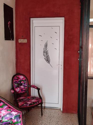 a door with a feather stencil on it next to a chair at Logement dans résidence principale Le Crès in Le Crès
