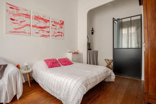 - une chambre avec un lit blanc et des oreillers rouges dans l'établissement L'échoppe de Sophie, à Le Bouscat