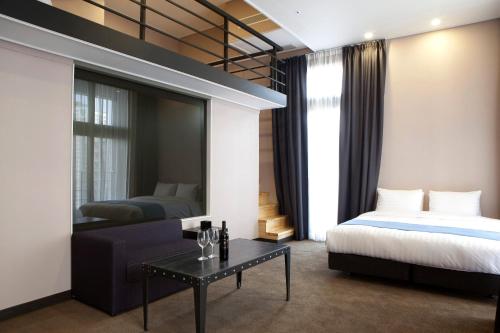 a bedroom with a bed and a couch and a mirror at S Stay Hotel Dongtan in Hwaseong