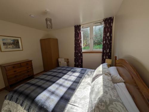 ein Schlafzimmer mit einem Bett und einem Fenster in der Unterkunft Strathpeffer Holiday Cottages in Strathpeffer