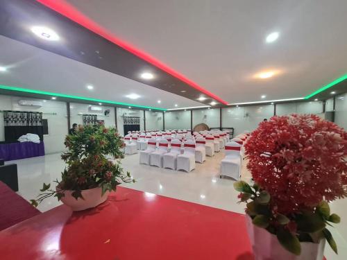 DhangadhiSitar Hotel and Restaurant的一间设有白色椅子和桌子的房间,鲜花盛开