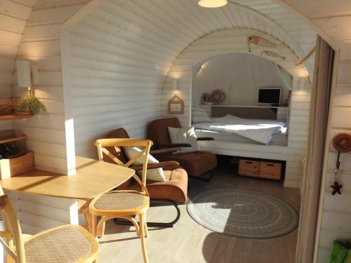 a room with a bed and a table and chairs at Tiny House De Boet, in Natuurgebied en vlakbij het Strand in Callantsoog