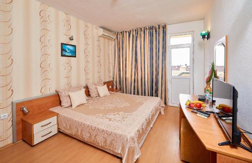 a bedroom with a bed and a desk with a television at Къща за гости Черно море in Sveti Vlas