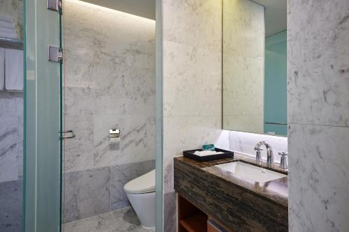 a bathroom with a sink and a toilet and a mirror at WE Hotel Jeju in Seogwipo
