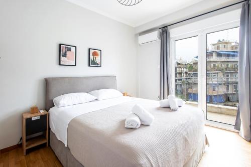 a bedroom with a bed with white sheets and a large window at Aris123 by Smart Cozy Suites - Apartments in the heart of Athens - 5 minutes from metro - Available 24hr in Athens