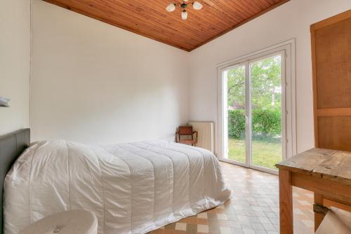 een witte slaapkamer met een bed en een raam bij Maison de vacances familiale proche de la plage in Andernos-les-Bains