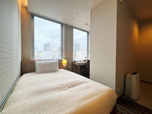 a bedroom with a large bed with a large window at Garden Hotel Shizuoka in Shizuoka