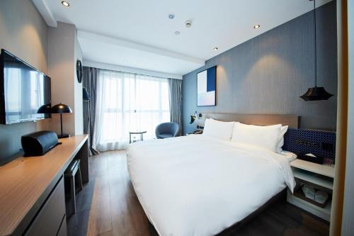 a hotel room with a large white bed and a desk at Orange Hotel Shanghai Hongkou Football Stadium Branch in Shanghai