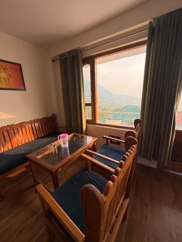 a living room with a table and chairs and a window at Cedar Valley Retreat in Jagatsukh