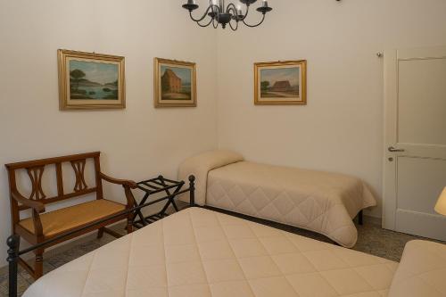 a bedroom with two beds and a chair and a chandelier at Casa di Aonio Paleario in Colle Val D'Elsa