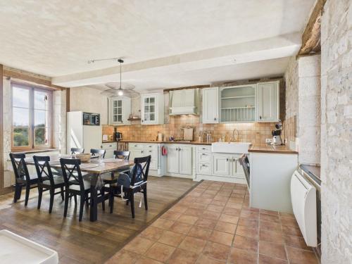 une cuisine avec des armoires blanches et une table et des chaises dans l'établissement À la campagne, belle maison pour 8 avec piscine, à Gabillou