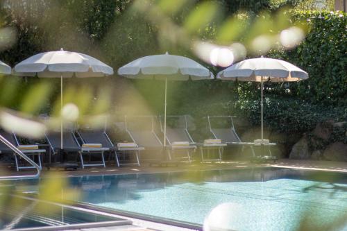 a group of chairs and umbrellas next to a pool at Hotel Sonnenhof in Merano