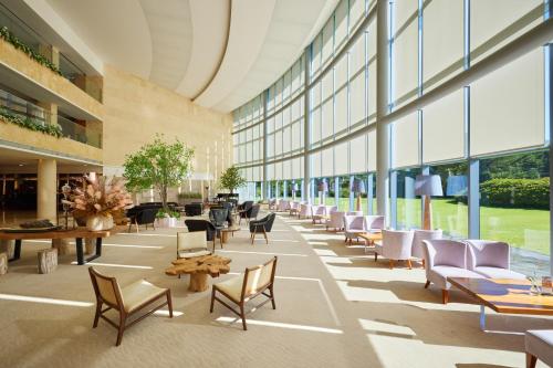 a lobby with chairs and tables and windows at WE Hotel Jeju in Seogwipo