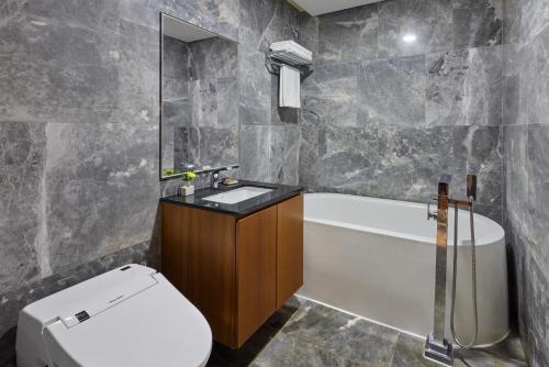 a bathroom with a toilet and a sink and a tub at WE Hotel Jeju in Seogwipo