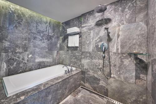 a bathroom with a shower and a tub at WE Hotel Jeju in Seogwipo