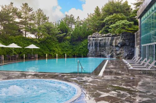 a pool at a resort with a waterfall at WE Hotel Jeju in Seogwipo