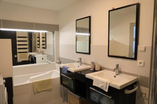 une salle de bain avec deux lavabos et deux miroirs dans l'établissement Vives les vacances, à Arques-la-Bataille