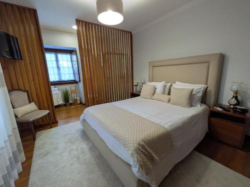 a bedroom with a large white bed and a window at Casa de Ladrido in Felgueiras
