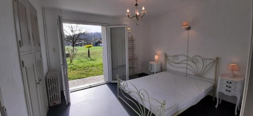 - une chambre avec un lit blanc et une porte coulissante en verre dans l'établissement Gîte près de Sarlat avec jardin et salon de massages, à Carsac-Aillac