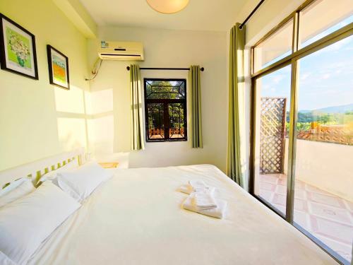 a bedroom with a white bed with a window at Cloud Tree Inn Boutique Guesthouse XiChong DaPeng ShenZhen 深圳大鹏西涌云树里民宿Yun Shu Li in Shenzhen