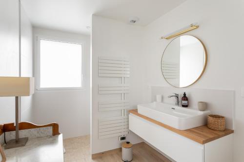 a white bathroom with a sink and a mirror at Le Belvédère - 12 min à pied de la plage in Pléneuf-Val-André