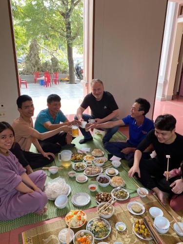 a group of people sitting around a table with food at NhaBoong-Homestay Riverside Ninh Binh in Ninh Binh