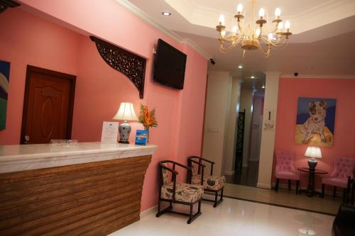 a salon with pink walls and a bar with chairs at Hotel Morobe in Lae