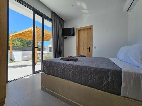 a bedroom with a bed and a large window at Myrteni Pool Villas in Ialyssos