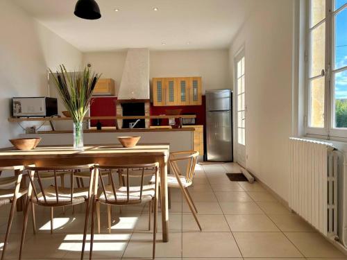 une cuisine avec une table avec des chaises et un réfrigérateur dans l'établissement Charmante maison en pierre, proche de St Émilion, à Montagne