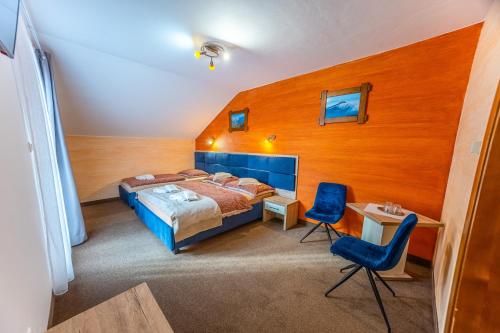 a bedroom with a bed and a desk and two chairs at Penzion Josu in Zuberec