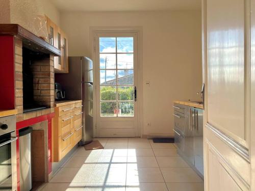 Il comprend une cuisine équipée d'un réfrigérateur et une grande fenêtre. dans l'établissement Charmante maison en pierre, proche de St Émilion, à Montagne