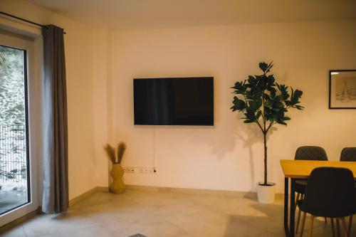 a living room with a television on the wall at HUGOS Design Apartment am Waldrand - ruhig & modern in Bensheim