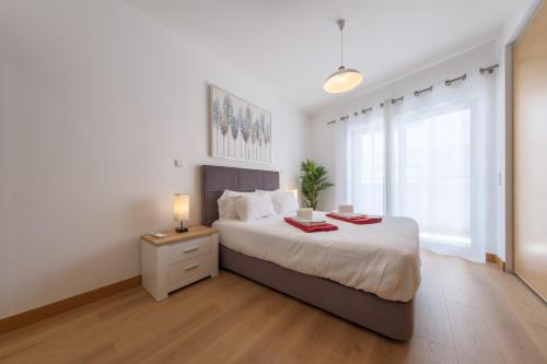 a white bedroom with a large bed with a night stand at Flor do Galvão in Lagos