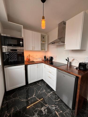 a kitchen with white cabinets and a black counter top at LE GOLDEN accès direct tramway Genève avec parking in Ambilly