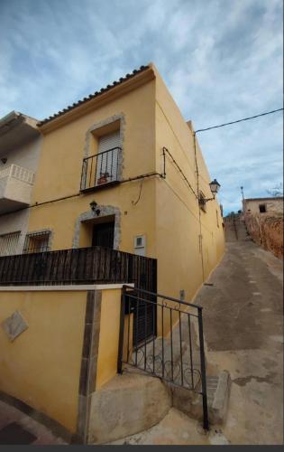a yellow building with a balcony and a staircase at Casa Rural La Parra in Ricote