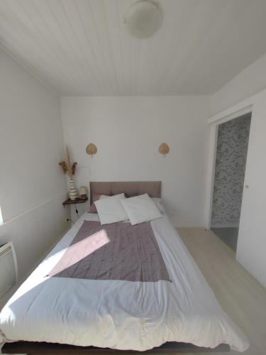 une chambre avec un grand lit dans une pièce blanche dans l'établissement La Golondrina, à Villefranche-sur-Saône