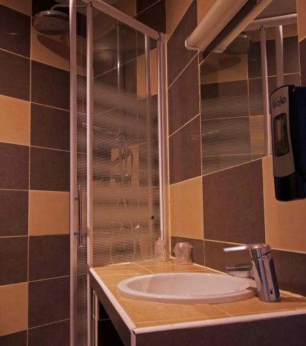 a bathroom with a sink and a glass shower at Le Strasbourg Hotel in Montpellier