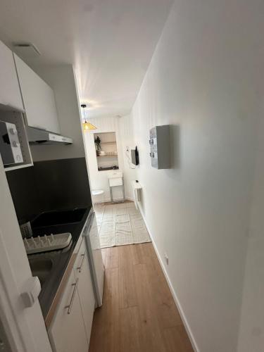a kitchen with white walls and a wooden floor at Studio refait à neuf, lumineux - 131 in Dax