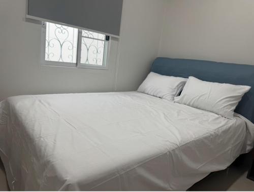 a large white bed with two pillows and a window at The Little House in Chaloklum
