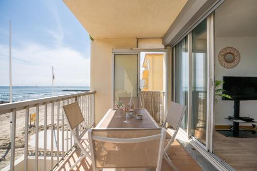 a balcony with a table and chairs and the ocean at Les Pieds dans l'eau YourHostHelper in Palavas-les-Flots