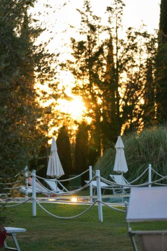 a group of lawn chairs with umbrellas in the grass at Hotel Relais Santa Genoveffa in Paganico