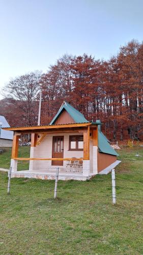 une petite maison avec un toit bleu dans un champ dans l'établissement Koliba, à Žabljak