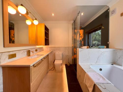a bathroom with a tub and a sink and a toilet at Luxuosa Vila Alvorninha in Alvorninha